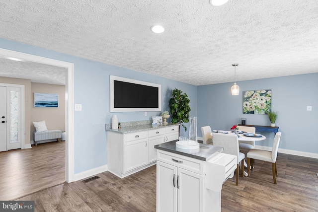 kitchen featuring baseboards, white cabinetry, and a textured ceiling