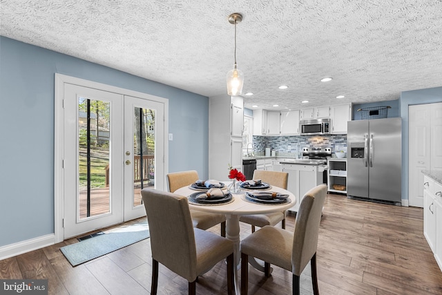 dining space with recessed lighting, wood finished floors, visible vents, french doors, and baseboards