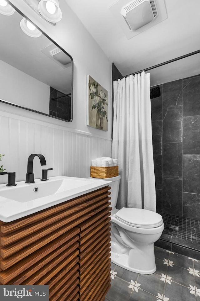 bathroom with wainscoting, a tile shower, toilet, tile patterned flooring, and visible vents