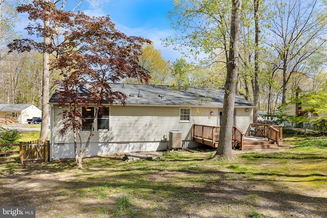 back of property with a wooden deck, a yard, central air condition unit, and fence