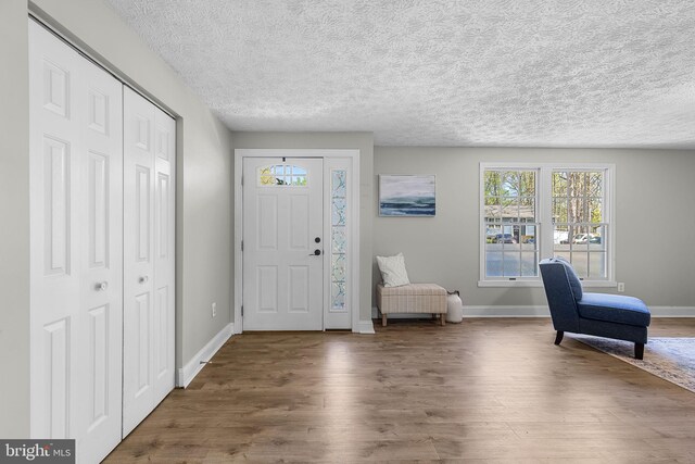 entryway with wood finished floors, a textured ceiling, and baseboards