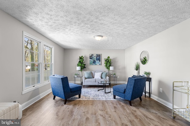 sitting room featuring wood finished floors, a textured ceiling, and baseboards
