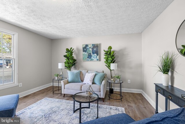 living area featuring a textured ceiling, wood finished floors, visible vents, and baseboards
