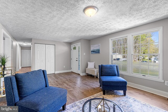 sitting room with baseboards, wood finished floors, and a textured ceiling