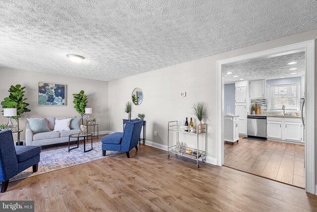 living area with light wood-style flooring, baseboards, and a textured ceiling