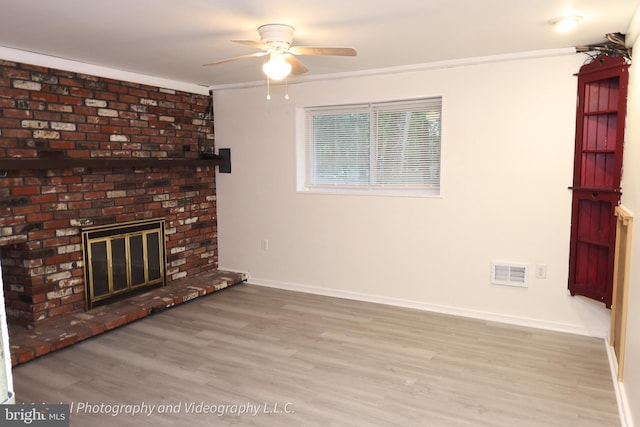 unfurnished living room with ceiling fan, wood finished floors, baseboards, a fireplace, and ornamental molding
