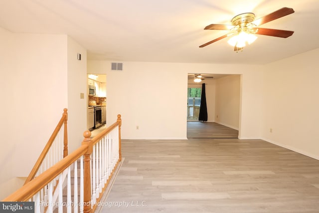 hall featuring light wood finished floors, an upstairs landing, and baseboards