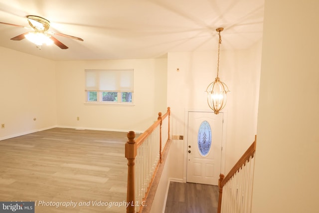 foyer with a chandelier, wood finished floors, a ceiling fan, and baseboards