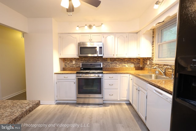 kitchen with appliances with stainless steel finishes, a sink, light wood-style floors, and white cabinetry