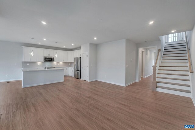 2963 Rambling Brook Ln, Crozet, VA 22932 - unfurnished living room featuring baseboards, a sink, recessed lighting, stairway, and light wood-style flooring