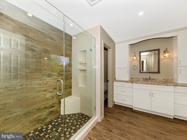 bathroom with a shower stall, recessed lighting, vanity, and wood finished floors