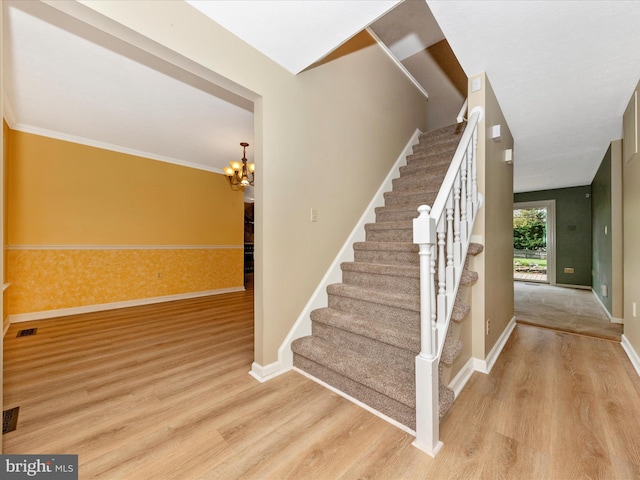stairway featuring wood finished floors, baseboards, visible vents, and a notable chandelier