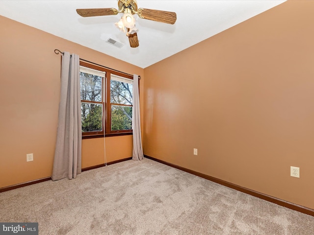 spare room featuring light carpet, visible vents, baseboards, and ceiling fan