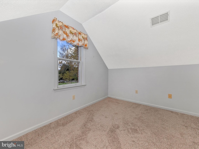 additional living space featuring carpet, baseboards, vaulted ceiling, and visible vents