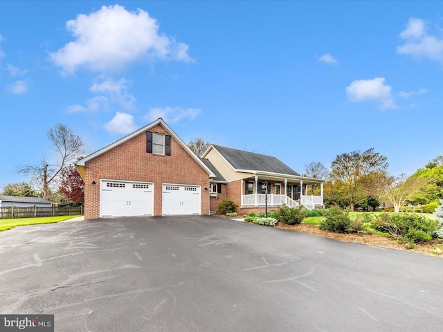 view of front of home featuring covered porch, fence, aphalt driveway, and brick siding