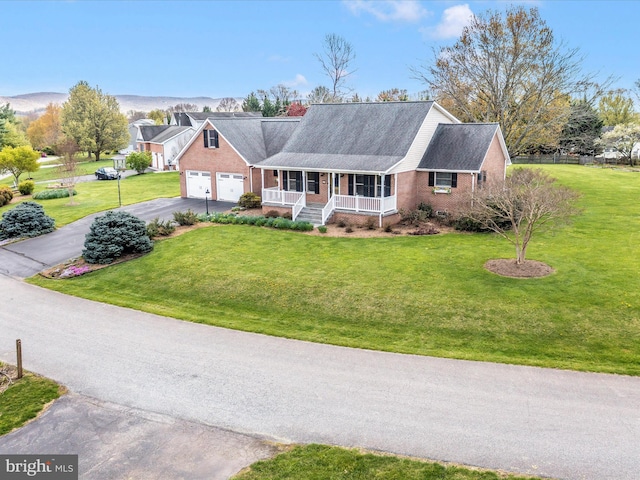 view of front of property with aphalt driveway, a front lawn, covered porch, brick siding, and a garage