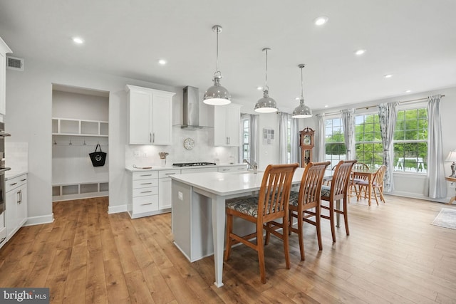 187 Boxelder Dr, Stafford, VA 22554 - kitchen featuring visible vents, wall chimney range hood, light countertops, stovetop, and an island with sink