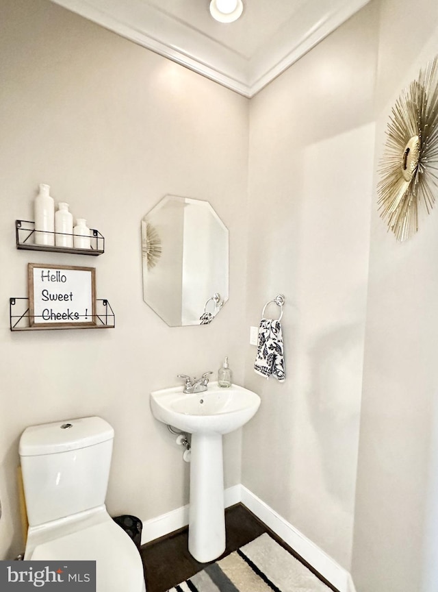 half bath featuring baseboards and toilet