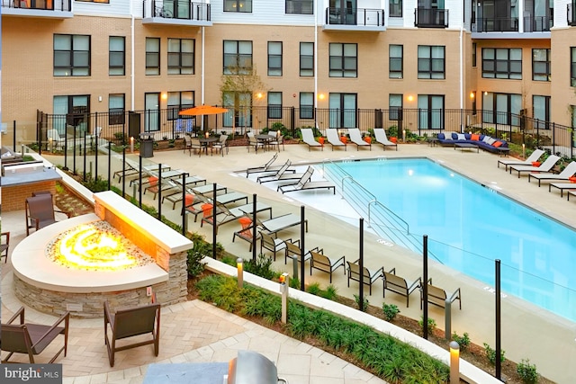 community pool featuring an outdoor fire pit, a patio area, and fence