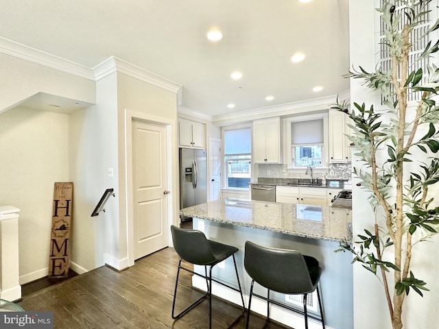 kitchen with a sink, a peninsula, crown molding, and appliances with stainless steel finishes
