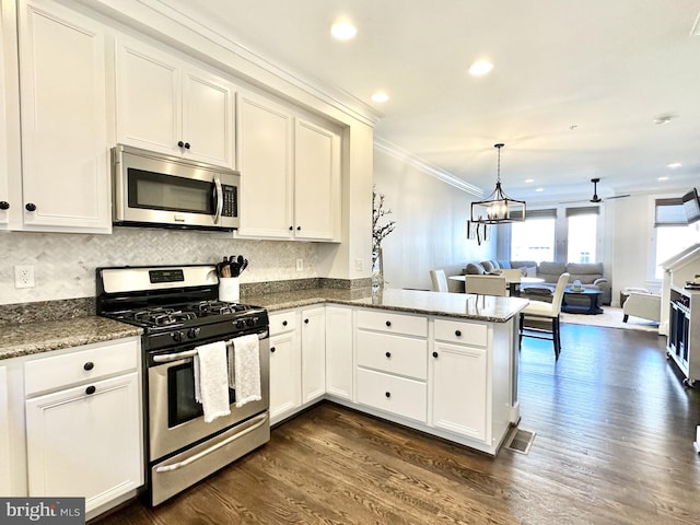 kitchen featuring open floor plan, white cabinets, dark wood-type flooring, appliances with stainless steel finishes, and ornamental molding