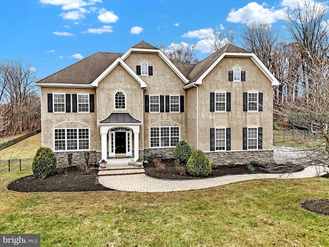 view of front of property featuring stone siding, a front yard, stucco siding, and fence