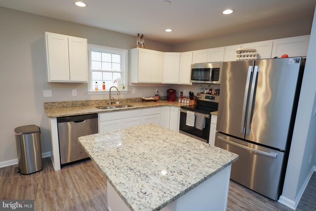 kitchen with light stone counters, a sink, white cabinetry, appliances with stainless steel finishes, and recessed lighting