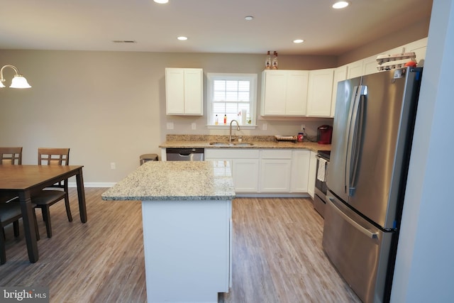 kitchen with white cabinetry, light wood finished floors, a sink, and appliances with stainless steel finishes
