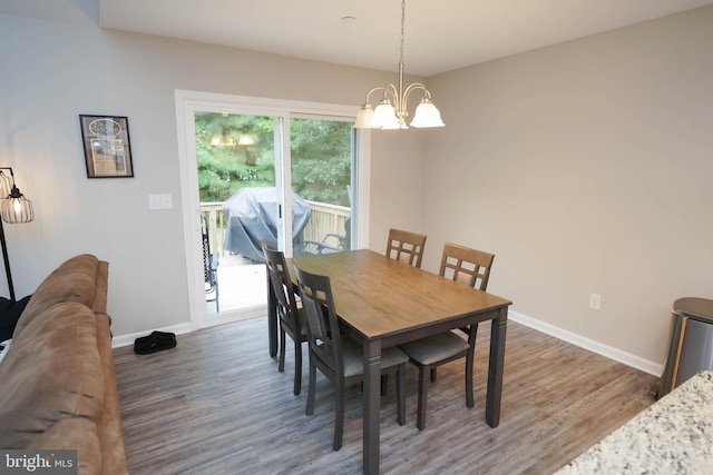 dining space with baseboards, a chandelier, and wood finished floors