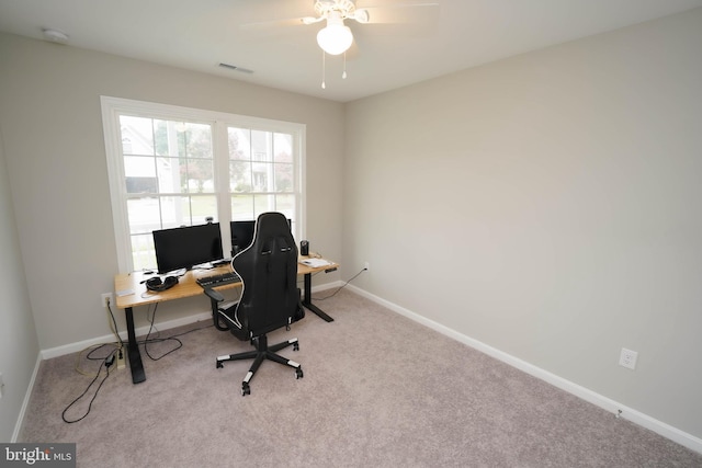 carpeted office space with baseboards, ceiling fan, and visible vents