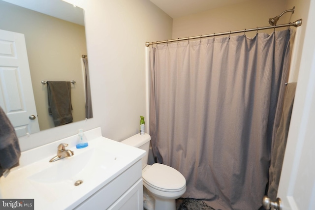 bathroom featuring toilet, a shower with shower curtain, and vanity