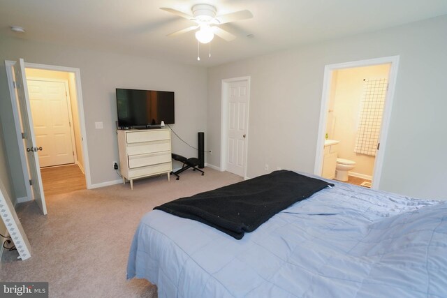 carpeted bedroom featuring ensuite bathroom and baseboards