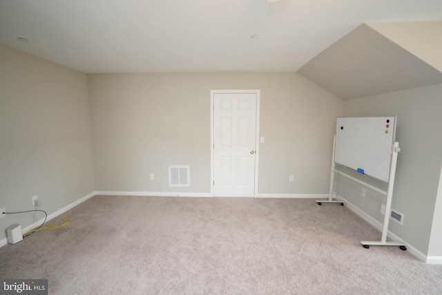 interior space featuring carpet floors, baseboards, lofted ceiling, and visible vents