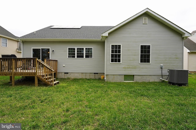 rear view of house with cooling unit, solar panels, a yard, and a wooden deck