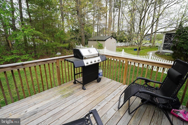 wooden deck featuring grilling area, an outdoor structure, fence, and a yard