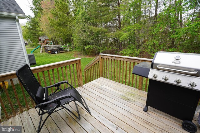wooden terrace featuring a playground, area for grilling, and a yard