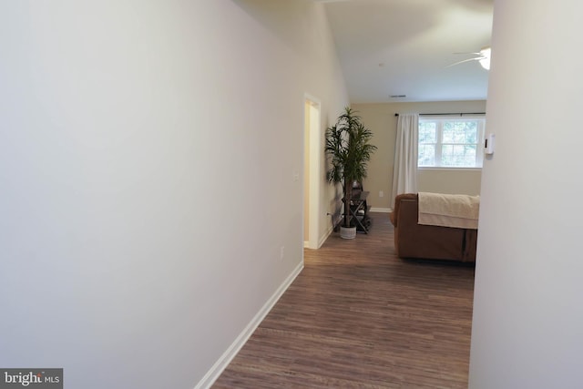 hallway featuring dark wood finished floors, baseboards, and lofted ceiling