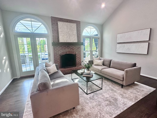 living area with baseboards, a brick fireplace, wood finished floors, and high vaulted ceiling