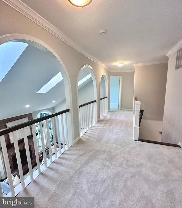 hall featuring crown molding, a skylight, carpet floors, baseboards, and an upstairs landing