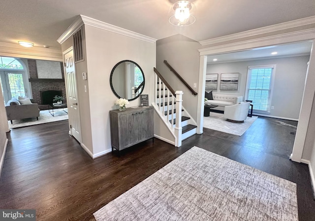foyer featuring a fireplace, baseboards, wood finished floors, ornamental molding, and stairway