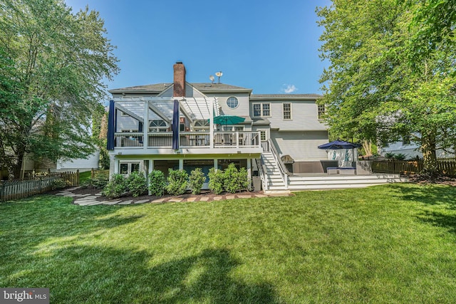 back of house with stairway, a lawn, a wooden deck, and a fenced backyard
