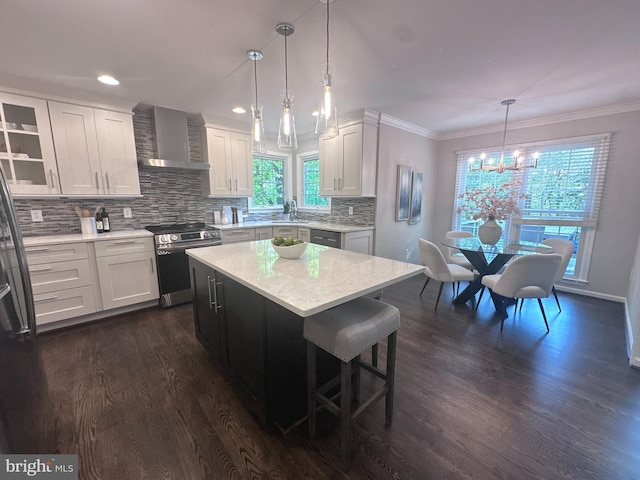 kitchen with wall chimney range hood, stainless steel electric stove, a sink, an inviting chandelier, and dark wood-type flooring