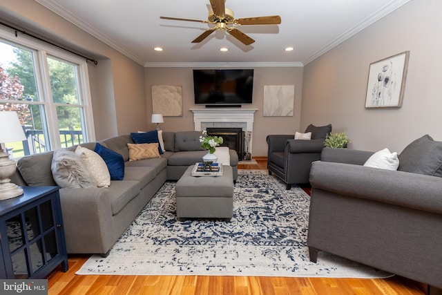 living room with wood finished floors, a fireplace with flush hearth, ornamental molding, ceiling fan, and recessed lighting