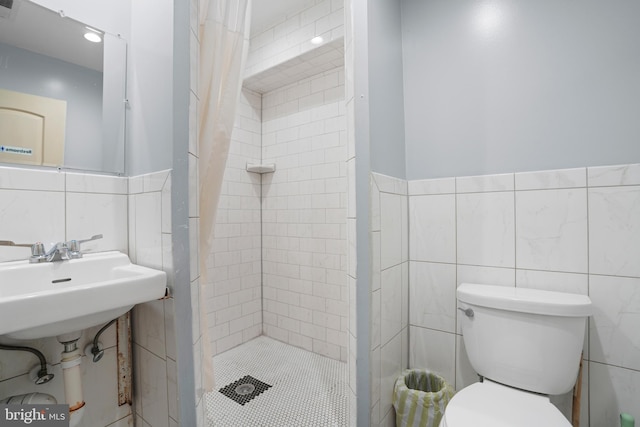 full bath with a sink, toilet, a wainscoted wall, tile walls, and a stall shower
