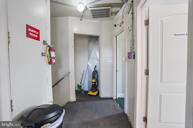 hallway featuring visible vents, carpet, and baseboards