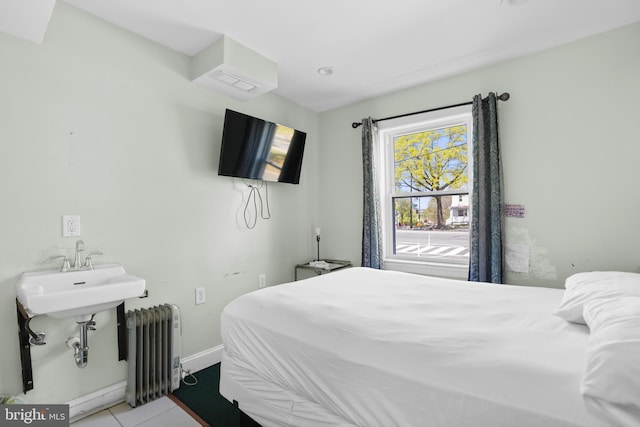 tiled bedroom featuring baseboards, a sink, and radiator