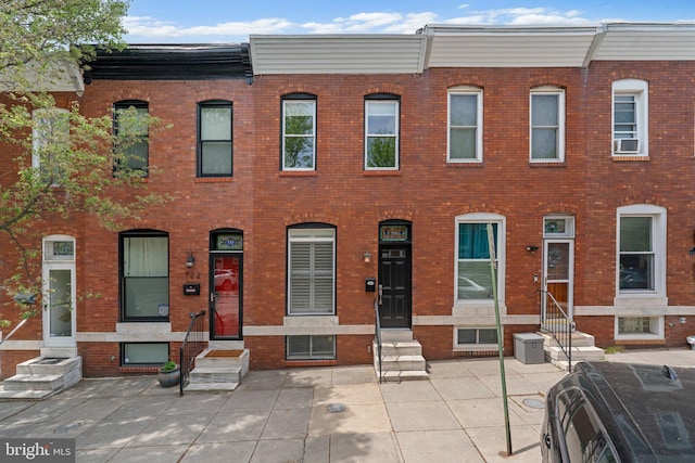 view of property featuring brick siding, cooling unit, and entry steps