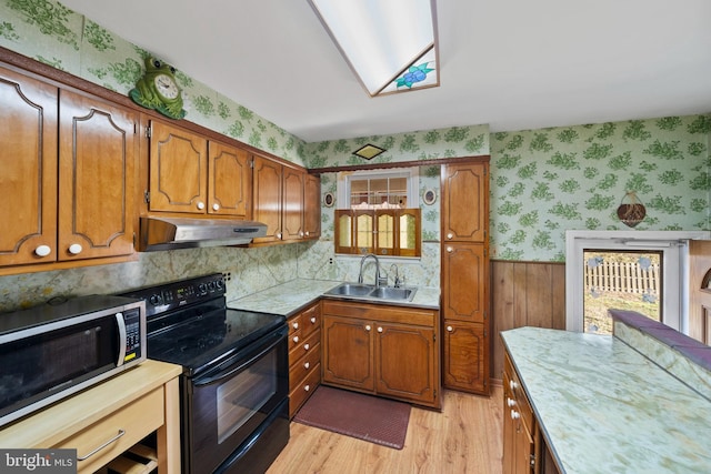 kitchen with a sink, under cabinet range hood, stainless steel microwave, wallpapered walls, and black / electric stove