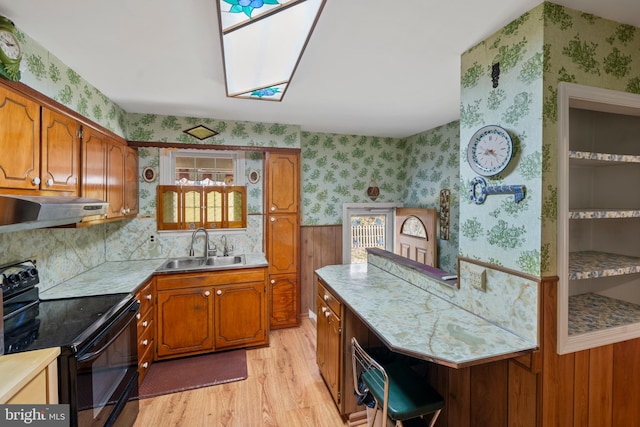 kitchen featuring wallpapered walls, brown cabinetry, black electric range oven, and under cabinet range hood
