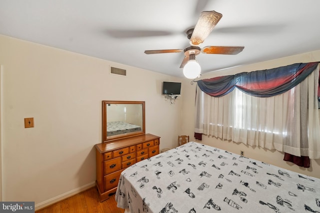 bedroom with baseboards, visible vents, wood finished floors, and ceiling fan